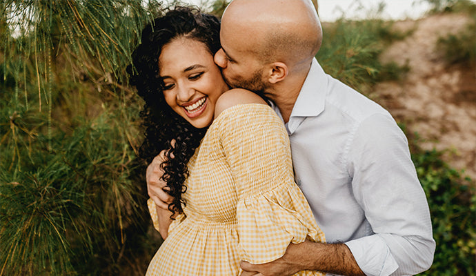 An expecting couple holding each other.